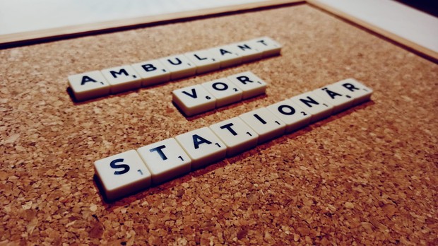 Scrabblebuchsteine legen auf Pinnwand die Wörter "Ambulant vor Stationär"