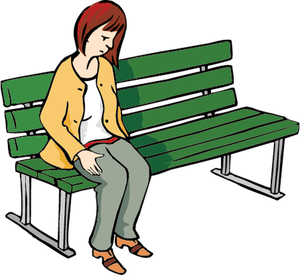Eine Frau sitzt mit traurigem Gesicht auf einer Bank, lässt den Kopf hängen und schaut zu Boden