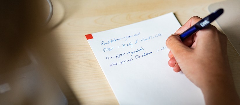 Mitarbeiterin macht sich Notizen zum Qualitätsmanagement
